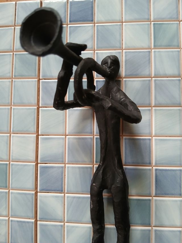 Escultura de metal de músico con trompeta