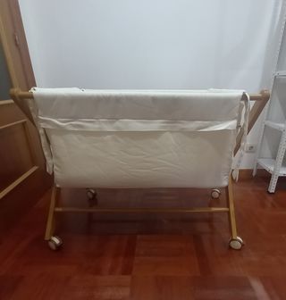 Cuna de bebé de madera con ruedas y mantas