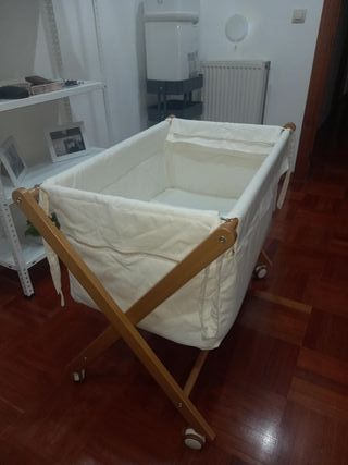 Cuna de bebé de madera con ruedas y mantas