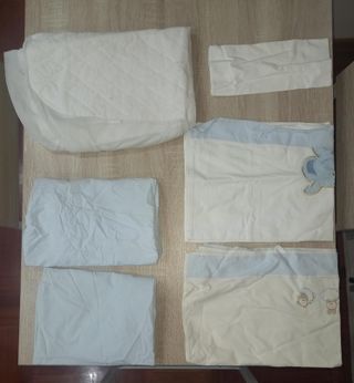 Cuna de bebé de madera con ruedas y mantas