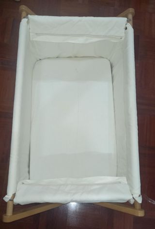 Cuna de bebé de madera con ruedas y mantas