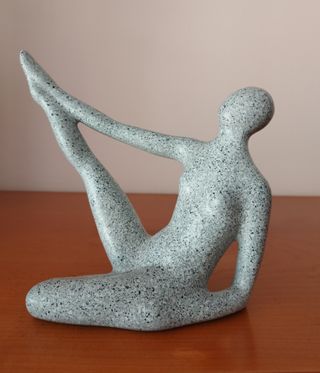 Figura yoga in pietra grigia