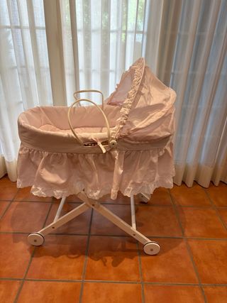 Cuna de bebé rosa con capota y ruedas