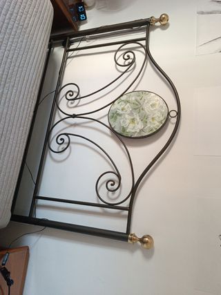 Cabecero de cama de forja con detalles dorados.