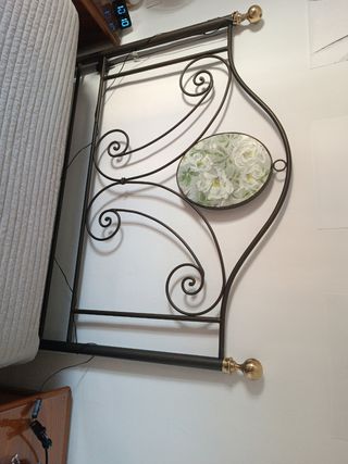 Cabecero de cama de forja con detalles dorados.