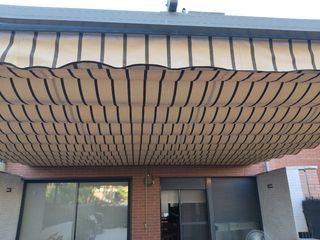 Pérgola extensible beige con rayas marrones.
