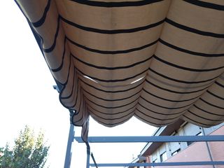 Pérgola extensible beige con rayas marrones.