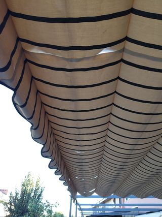 Pérgola extensible beige con rayas marrones.
