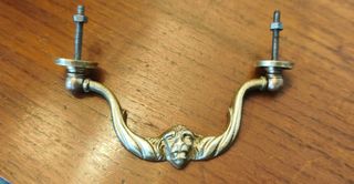 Tirador antiguo de bronce con cara de león.