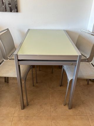 Mesa de cristal y metal plateado.
