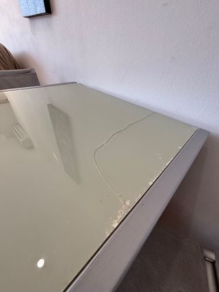 Mesa de cristal y metal plateado.

