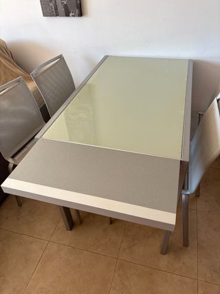 Mesa de cristal y metal plateado.
