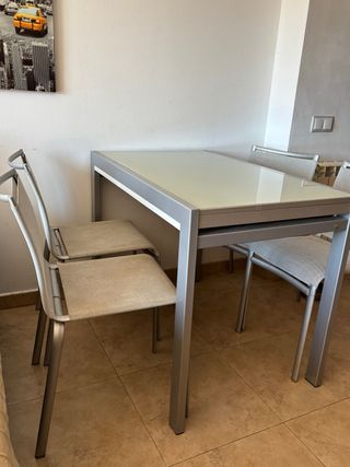 Mesa de cristal y metal plateado.
