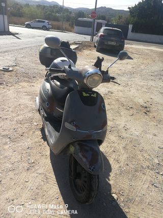 Moto 125cc gris con baúl y casco