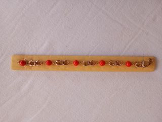 Pulsera chapada en oro de 18 k con cuentas rojas.
