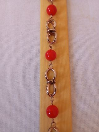Pulsera chapada en oro de 18 k con cuentas rojas.