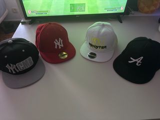 Gorra New era roja, acompañada con otras tres