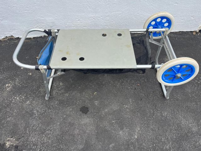 Carrito de playa con mesa.  Tiene una pieza rota.