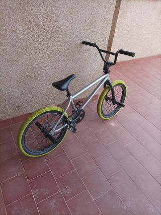 Bici BMX plateada con ruedas amarillas negociable 