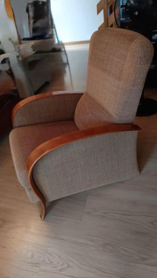 Sillón tapizado  con reposabrazos de madera.