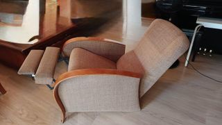 Sillón tapizado  con reposabrazos de madera.