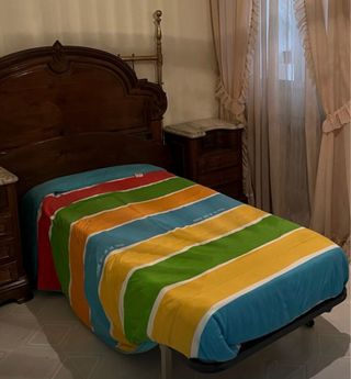 Mueble de madera con cama y colcha colorida