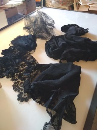 Diverse coperte in pizzo nero per oggetti di scena