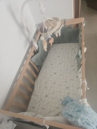 Cuna de madera con móvil de animales.
