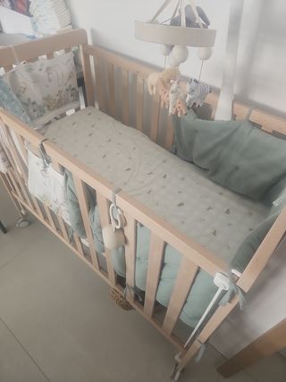 Cuna de madera con móvil de animales.
