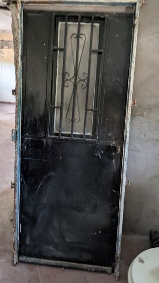 Puerta metálica negra con reja