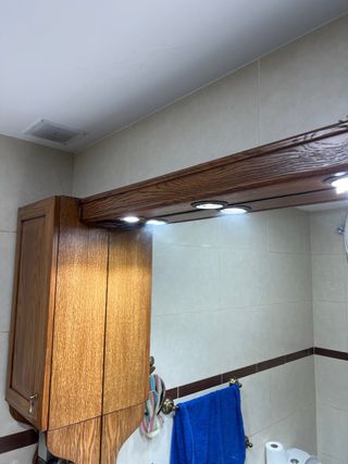 Mueble de baño de madera oscura y mármol. Con luz.