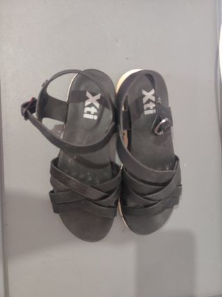 Sandalias negras de tiras con suela blanca.