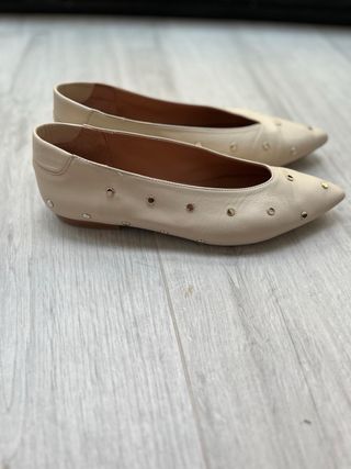 Zapatos planos beige con tachuelas doradas
