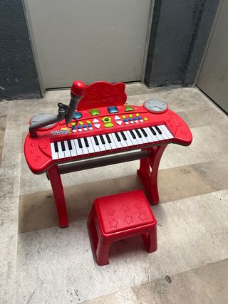 Piano electrónico rojo con micrófono y banqueta