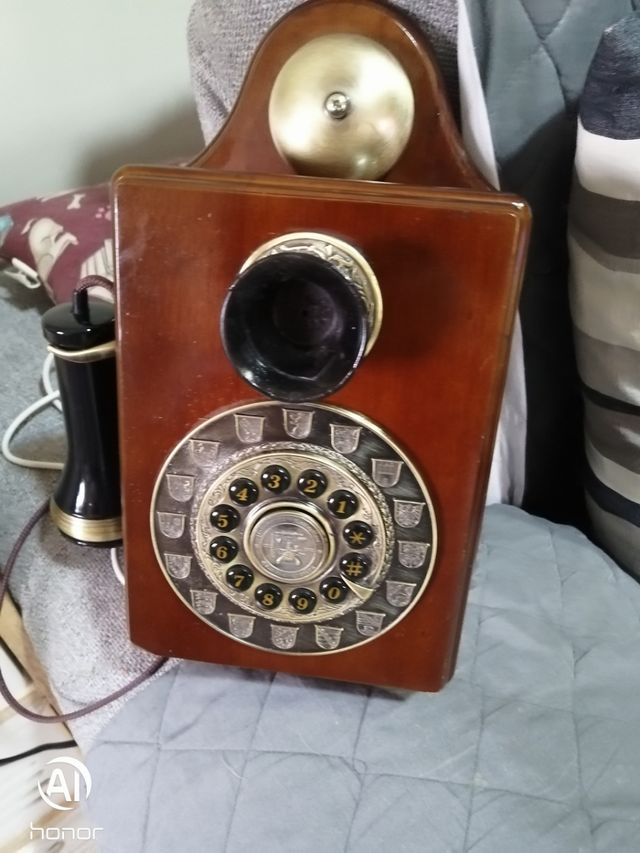 Telefono antico in legno con parete dorata