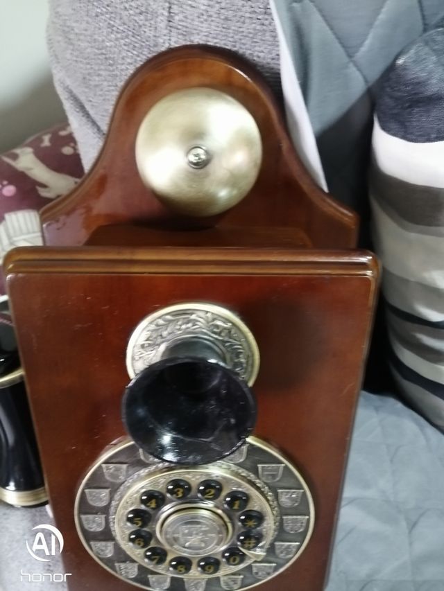 Telefono antico in legno con parete dorata