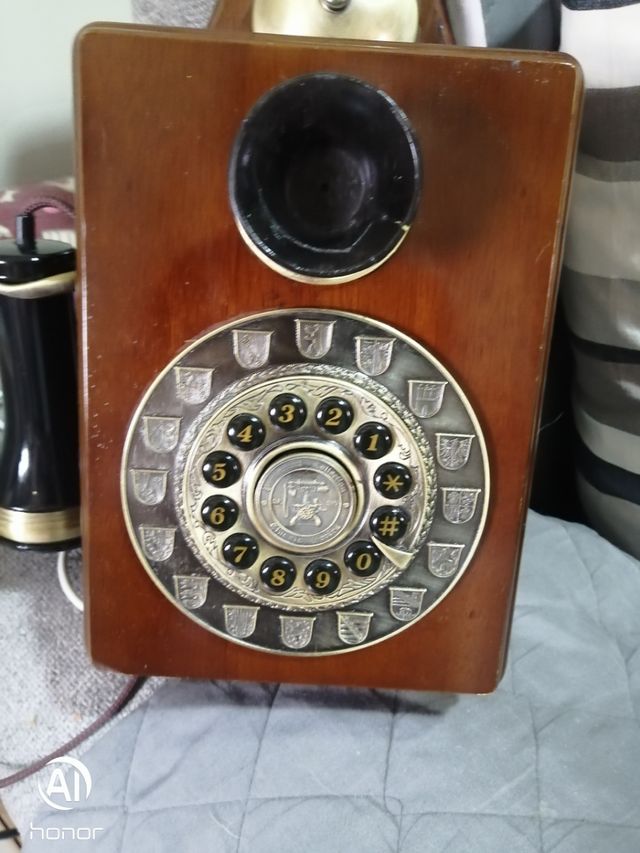 Telefono antico in legno con parete dorata