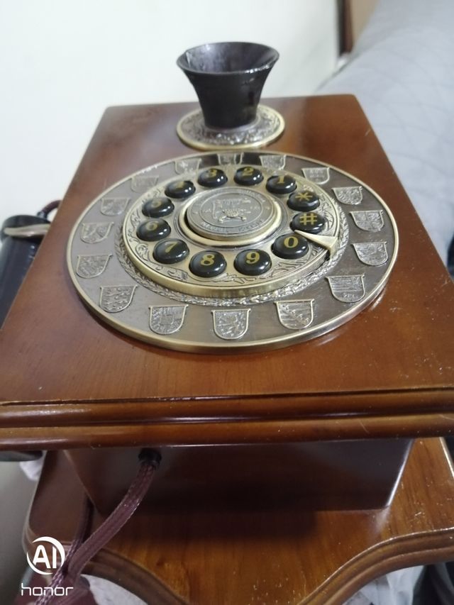 Telefono antico in legno con parete dorata