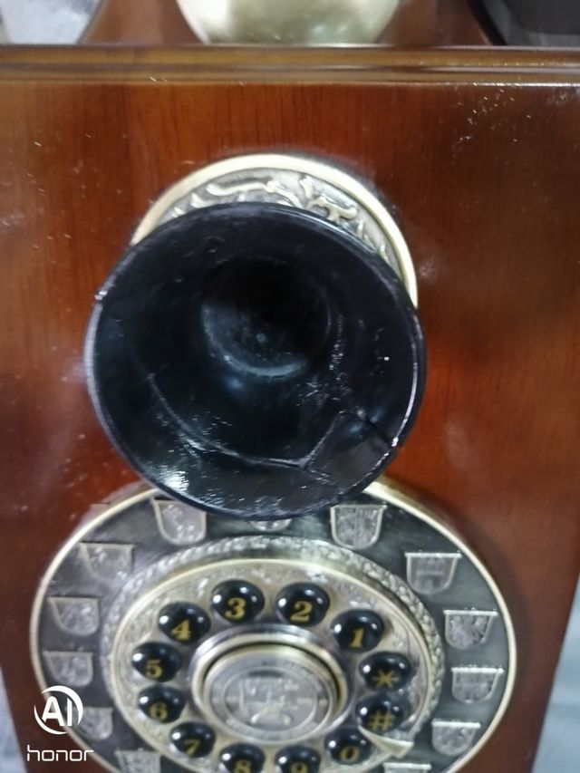 Telefono antico in legno con parete dorata
