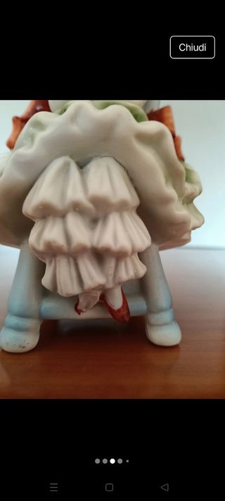 Bambola Capodimonte seduta su sedia