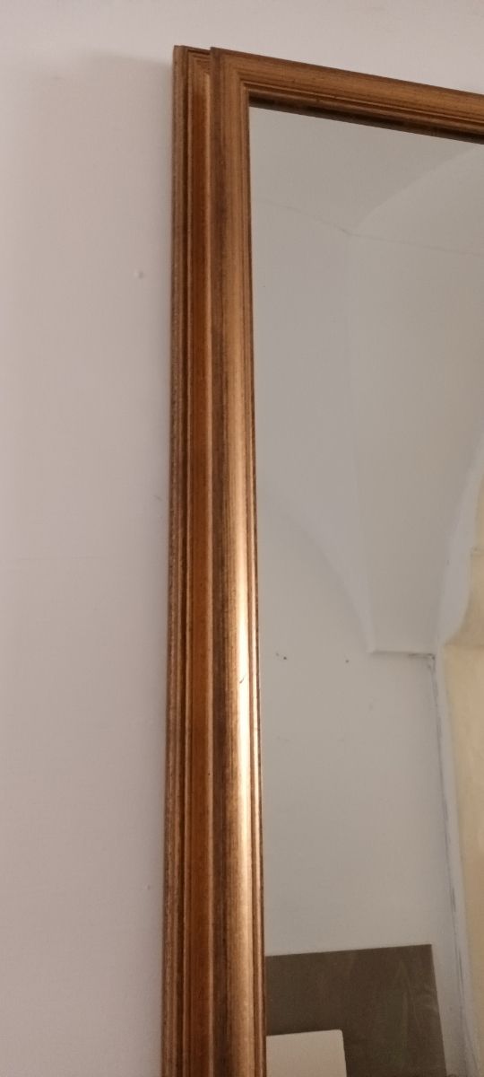 Specchio con cornice in legno dorato.