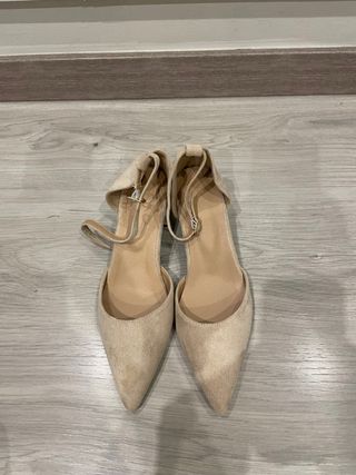Zapatos de tacón beige y negros con diamantes.