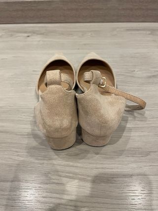 Zapatos de tacón beige y negros con diamantes.