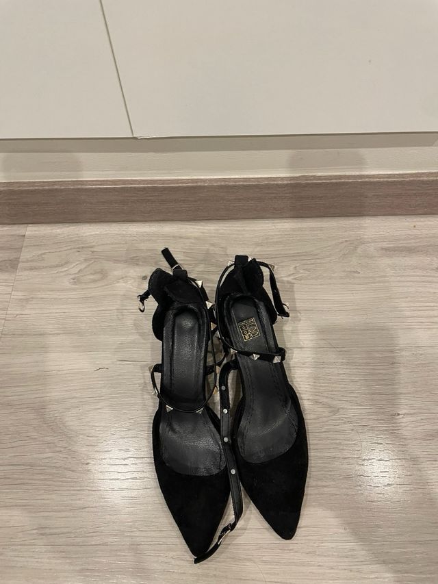 Zapatos de tacón beige y negros con diamantes.