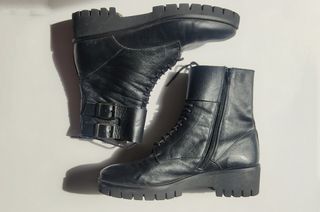 Botas negras de piel con cordones y hebillas.
