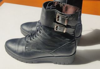 Botas negras de piel con cordones y hebillas.