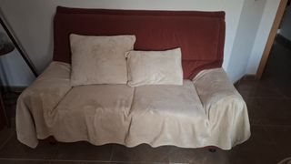Sofá de tela beige y rojo con manta