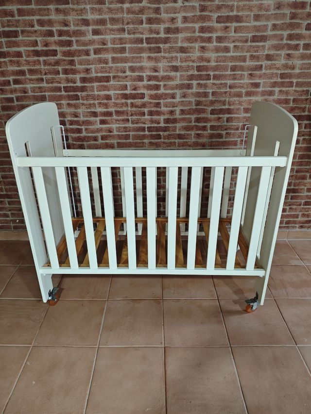 Cuna de bebé blanca con ruedas.