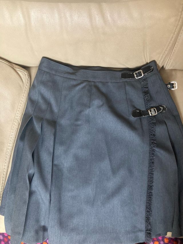 Falda plisada gris con hebillas.
