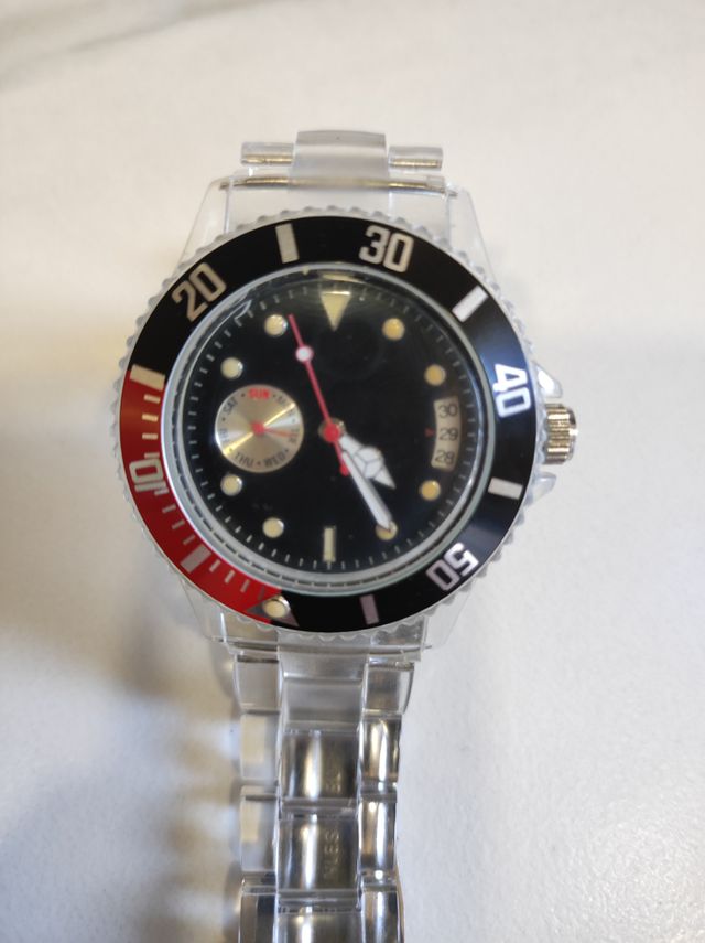 Reloj transparente con detalles en rojo y negro.